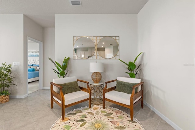 living area with tile patterned floors, visible vents, and baseboards