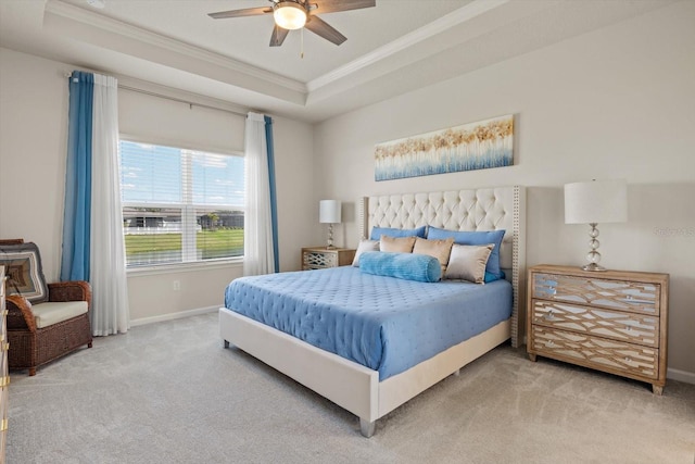 carpeted bedroom with baseboards, a tray ceiling, a ceiling fan, and ornamental molding