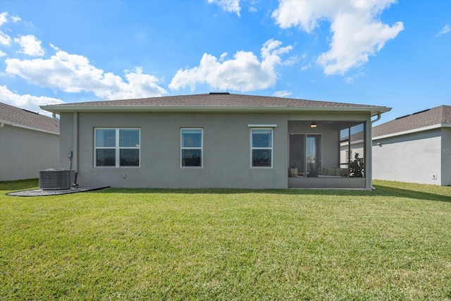 rear view of house with central AC unit, a lawn, a sunroom, and stucco siding