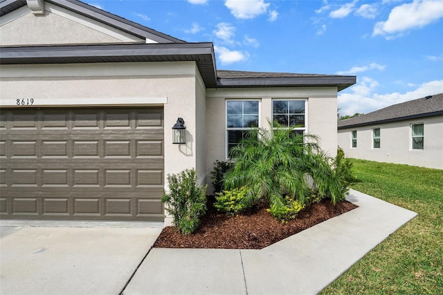 view of front facade with a garage, driveway, a front lawn, and stucco siding