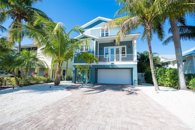 raised beach house featuring a garage, french doors, and decorative driveway