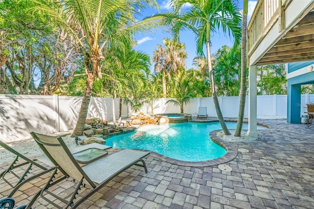 view of swimming pool featuring a fenced backyard, a pool with connected hot tub, and a patio