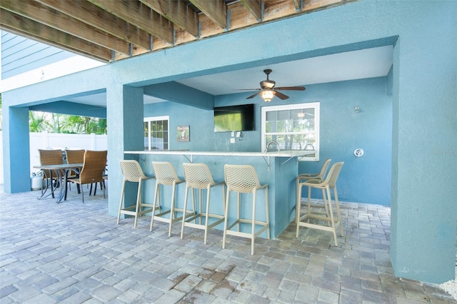 view of patio featuring a bar, ceiling fan, and fence