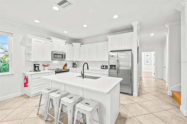 kitchen featuring stainless steel appliances, light countertops, a kitchen island with sink, and white cabinets