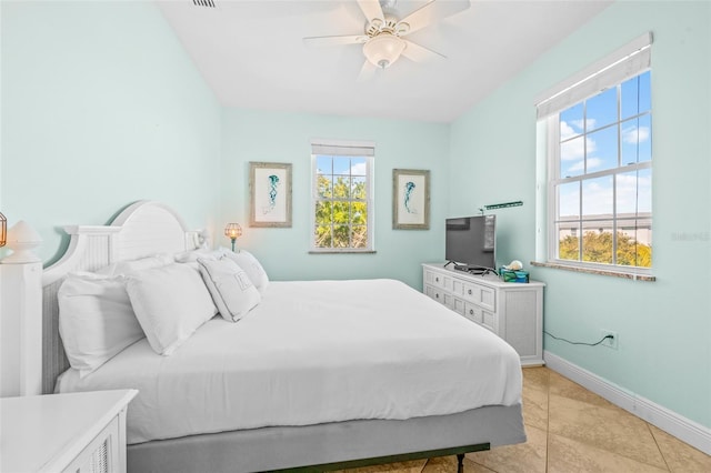 bedroom with light tile patterned floors, multiple windows, a ceiling fan, and baseboards