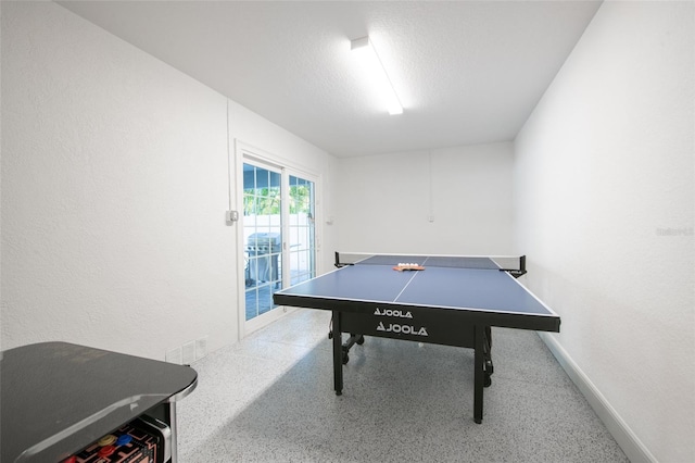 game room with a textured wall, baseboards, a textured ceiling, and speckled floor