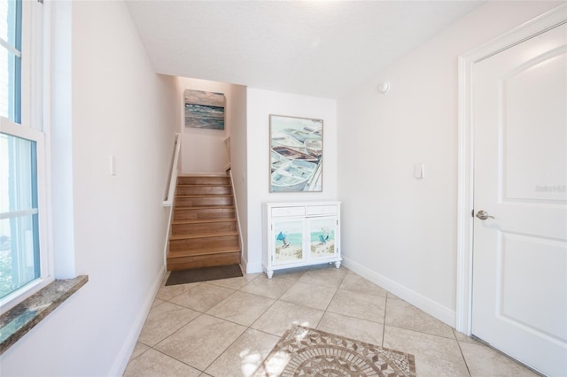 stairway with tile patterned flooring, baseboards, and a textured ceiling