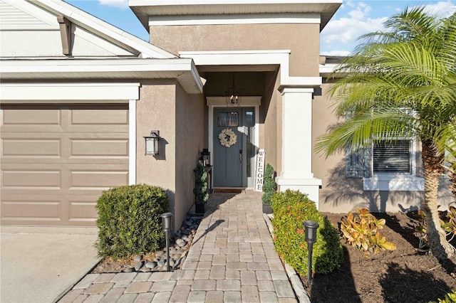 view of exterior entry featuring an attached garage and stucco siding