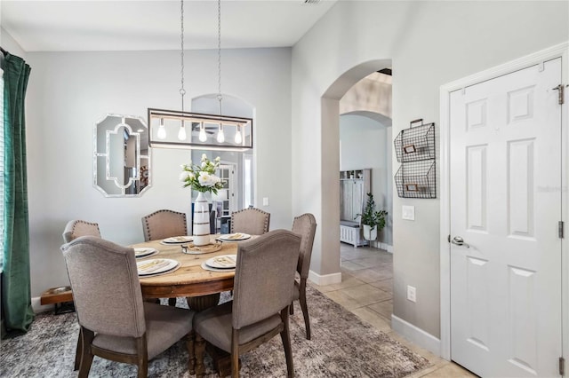 dining room with arched walkways, baseboards, and light tile patterned floors