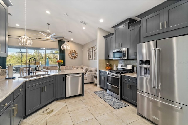 kitchen featuring light tile patterned floors, lofted ceiling, stainless steel appliances, a sink, and backsplash