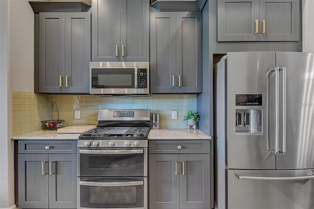 kitchen featuring appliances with stainless steel finishes, gray cabinets, light stone counters, and tasteful backsplash