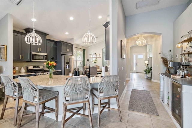 kitchen with an inviting chandelier, appliances with stainless steel finishes, a breakfast bar, and arched walkways