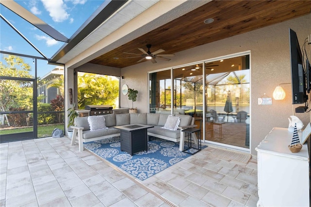 view of patio featuring ceiling fan, glass enclosure, an outdoor kitchen, and an outdoor hangout area