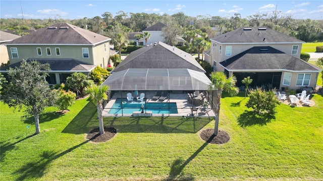 rear view of property featuring glass enclosure, a lawn, a patio, and an outdoor pool