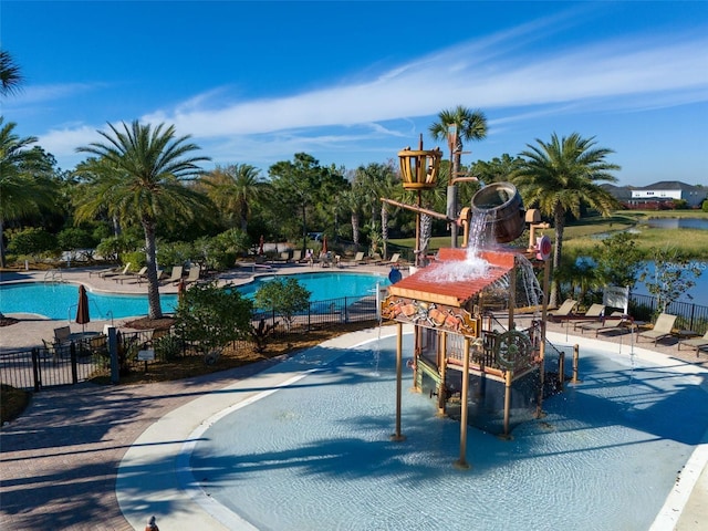 community pool with a patio area and fence