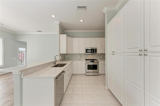 kitchen featuring stainless steel appliances, white cabinetry, a sink, and a peninsula