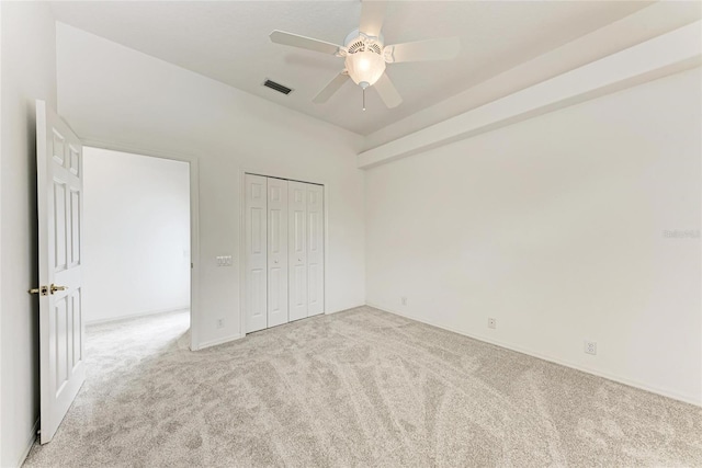 unfurnished bedroom with light carpet, a ceiling fan, and a closet