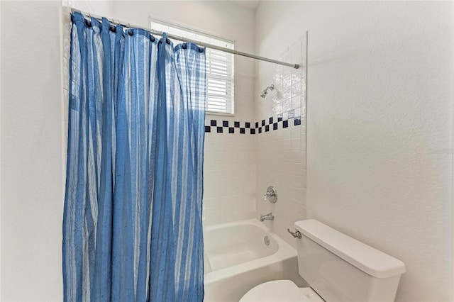 bathroom with toilet, shower / tub combo, and a textured wall