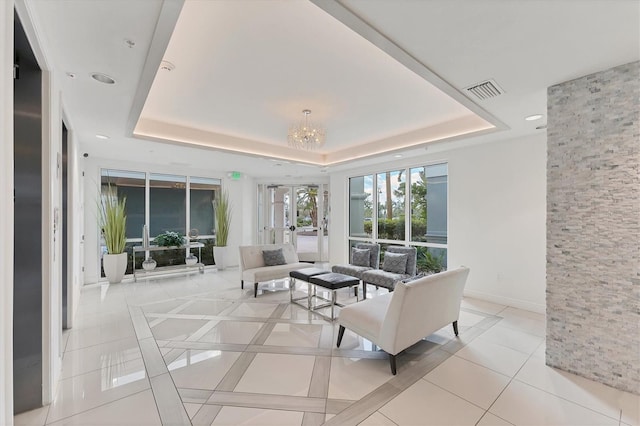 living room with an inviting chandelier, tile patterned flooring, visible vents, and a raised ceiling