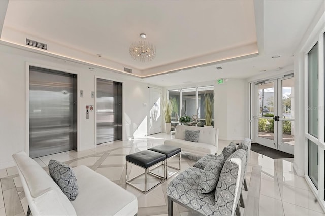 living area featuring baseboards, a tray ceiling, visible vents, and elevator