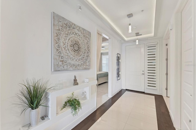 entryway featuring a raised ceiling and baseboards