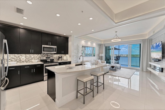 kitchen featuring appliances with stainless steel finishes, dark cabinetry, visible vents, and a breakfast bar area