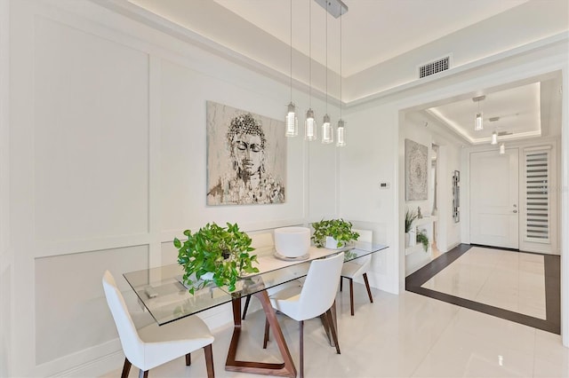 dining room with tile patterned flooring, a raised ceiling, visible vents, and a decorative wall