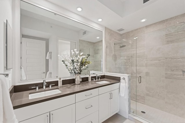 full bathroom with double vanity, a stall shower, a sink, and recessed lighting