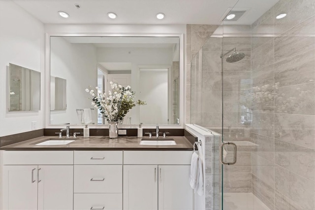 full bathroom featuring visible vents, a sink, a shower stall, and double vanity