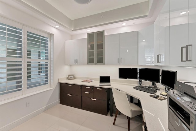 office space featuring baseboards, a raised ceiling, built in desk, and recessed lighting