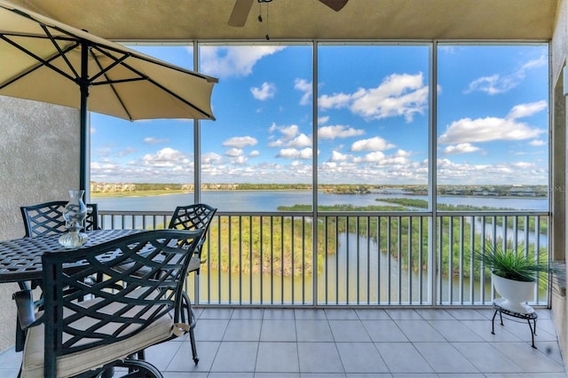 sunroom / solarium with a water view and a ceiling fan