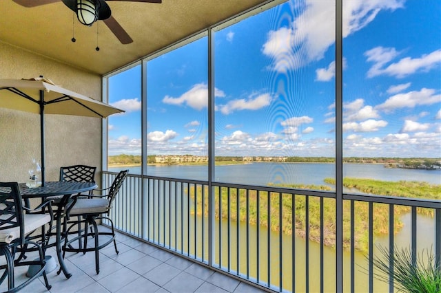 sunroom / solarium with a ceiling fan and a water view