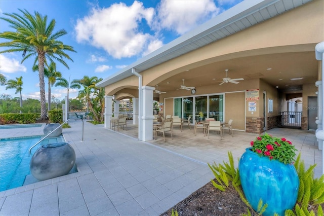 exterior space with a community pool, outdoor dining area, and a ceiling fan