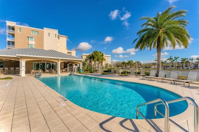 pool with fence, a ceiling fan, and a patio