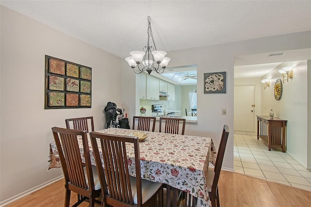 dining area featuring a textured ceiling, a chandelier, and light wood-style flooring