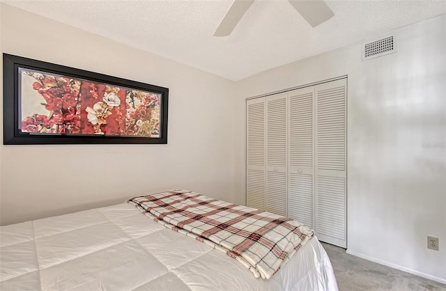 bedroom featuring carpet, a textured ceiling, visible vents, and a closet