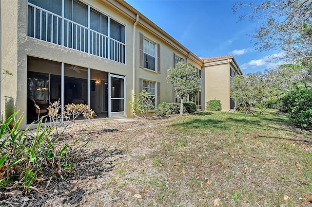 back of house with a lawn and stucco siding