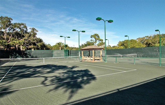 view of tennis court with fence and a gazebo