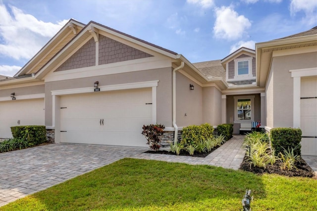 view of front facade with a front lawn, decorative driveway, an attached garage, and stucco siding