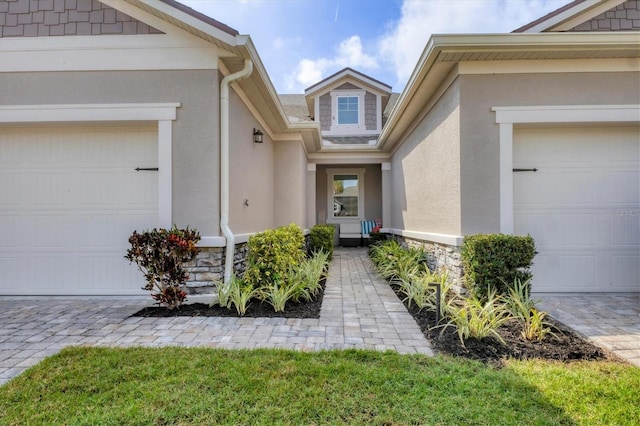 property entrance with a garage, stone siding, and stucco siding