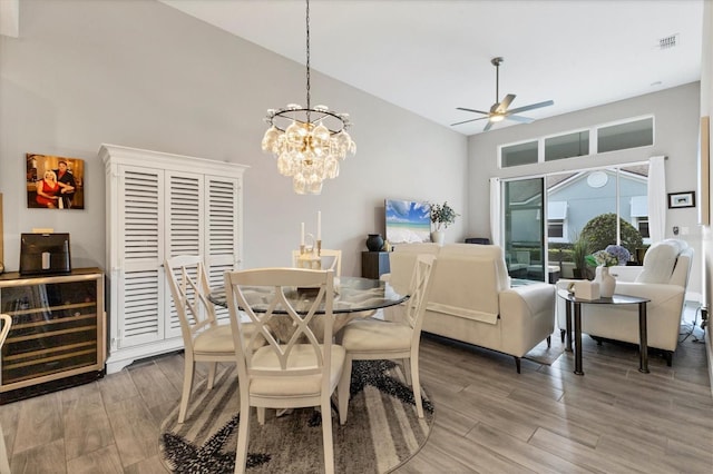 dining room featuring beverage cooler, visible vents, a towering ceiling, and wood finished floors