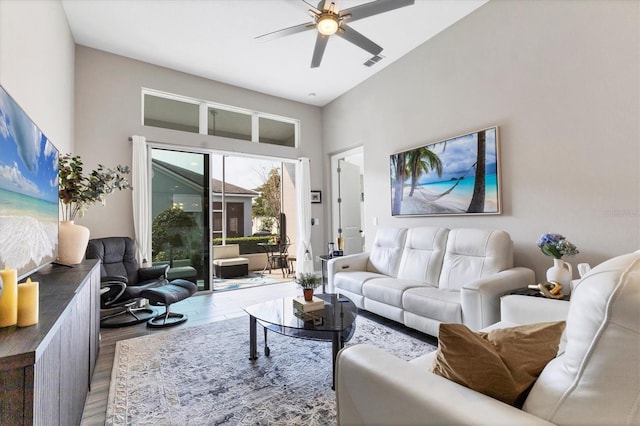 living room with ceiling fan, a towering ceiling, wood finished floors, and visible vents