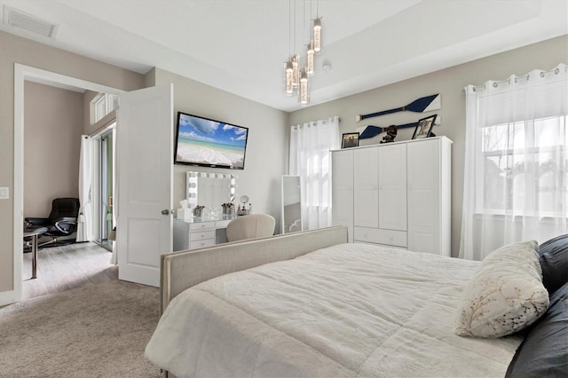 bedroom with light colored carpet, visible vents, and multiple windows