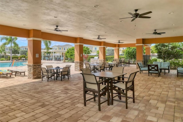 view of patio / terrace featuring ceiling fan, a community pool, fence, and outdoor dining space