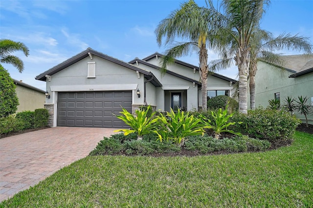 view of front of home with a front lawn, decorative driveway, an attached garage, and stucco siding