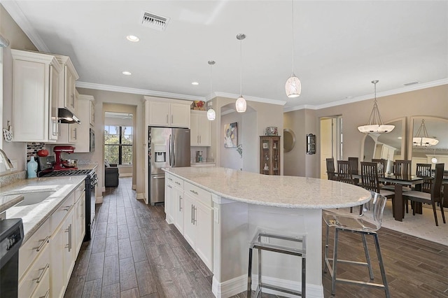 kitchen with visible vents, hanging light fixtures, a sink, a kitchen island, and black appliances