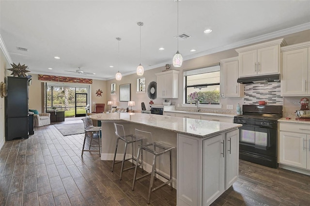 kitchen featuring under cabinet range hood, black range with gas cooktop, a kitchen island, and visible vents