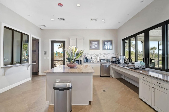 kitchen featuring visible vents, light stone counters, white cabinets, and stainless steel dishwasher