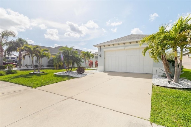 view of front of house with driveway, a front lawn, an attached garage, and stucco siding