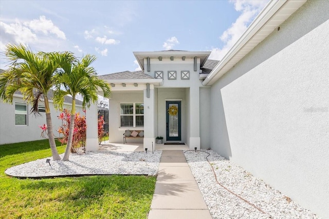 entrance to property with a lawn and stucco siding